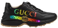 Gucci women’s Rhyton sneaker in black leather with iridescent Gucci logo and chunky rubber sole.

