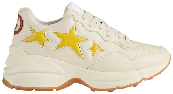 Gucci Wmns Rhyton 'Stars' sneaker featuring yellow star graphics on white vegan leather upper with ivory accents.

