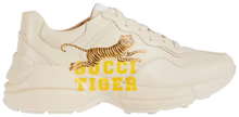 Gucci Wmns Rhyton 'Gucci Tiger' sneaker featuring retro tiger print on ivory leather upper with chunky sole.

