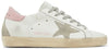 Golden Goose Superstar women’s sneaker in white leather with pink heel tab and distressed rubber sole.